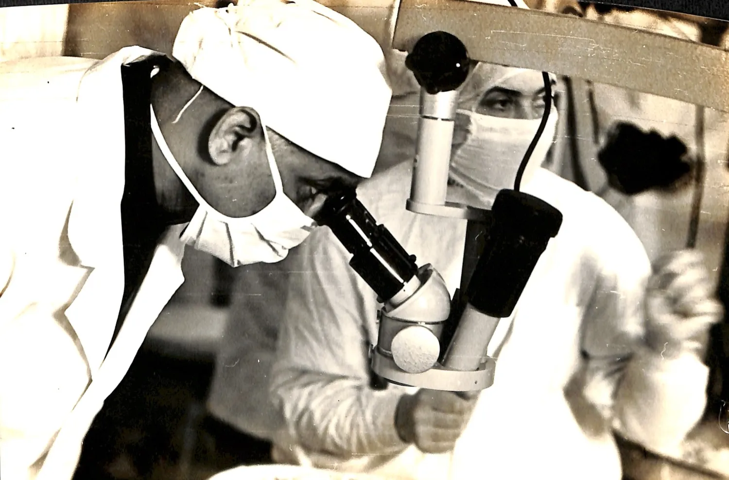 Dr. P. Siva Reddy at an early binocular operating microscope, mid-surgery