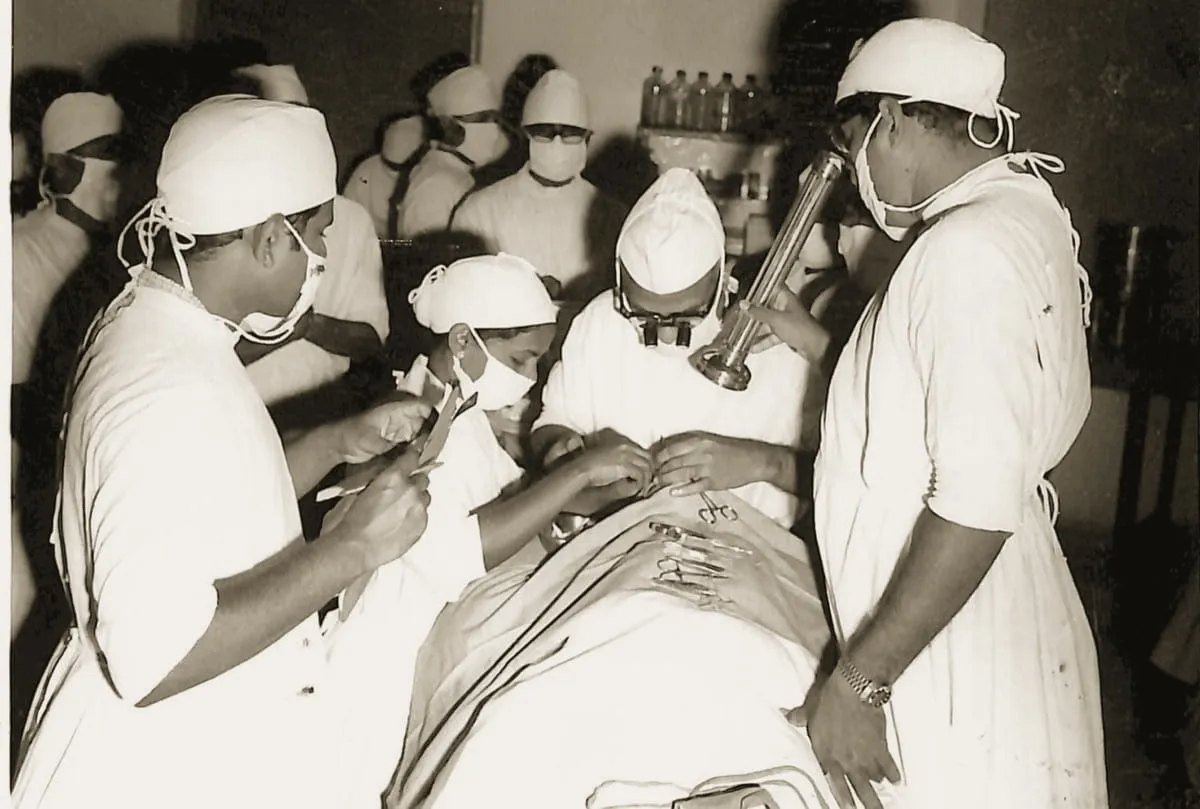 Dr. P. Siva Reddy operating under a head light, ringed by masked students and observers
